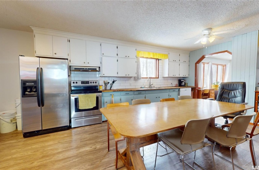 Kitchen with sink, backsplash, light wood-type flooring, stainless steel appliances, and ceiling fan