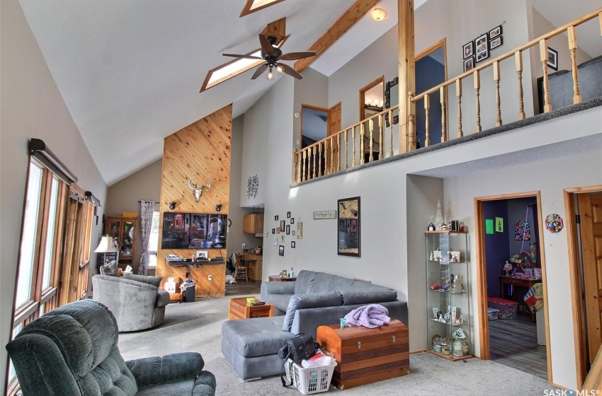 Carpeted living room with ceiling fan and high vaulted ceiling