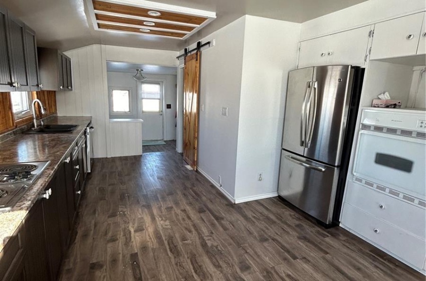 Kitchen featuring sink, dishwashing machine, a healthy amount of sunlight, and dark wood-type flooring