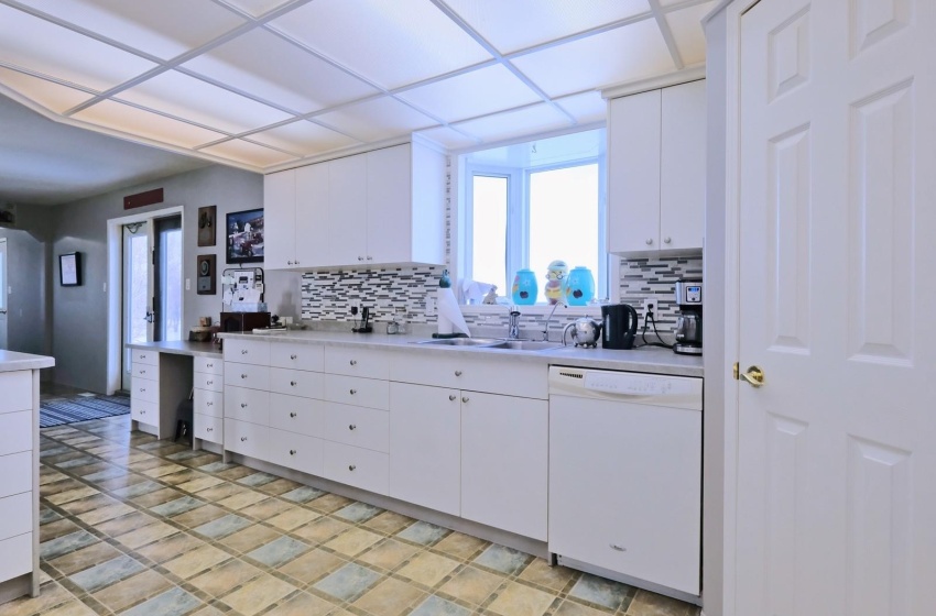 Kitchen featuring tasteful backsplash, white cabinets, light tile flooring, and white dishwasher