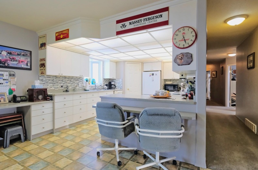 Kitchen featuring backsplash, light tile floors, white cabinetry, white refrigerator, and a kitchen bar