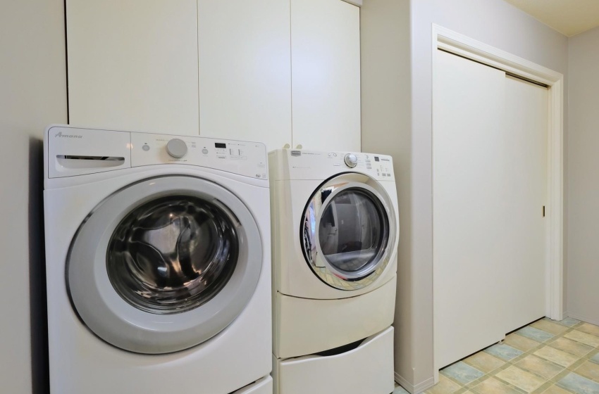 Laundry area with independent washer and dryer and light tile flooring