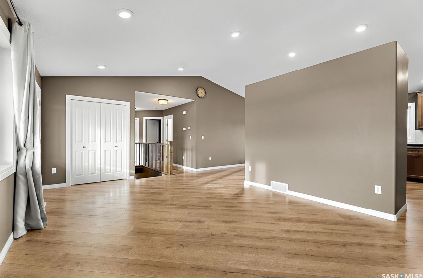 Unfurnished room with light wood-type flooring and vaulted ceiling