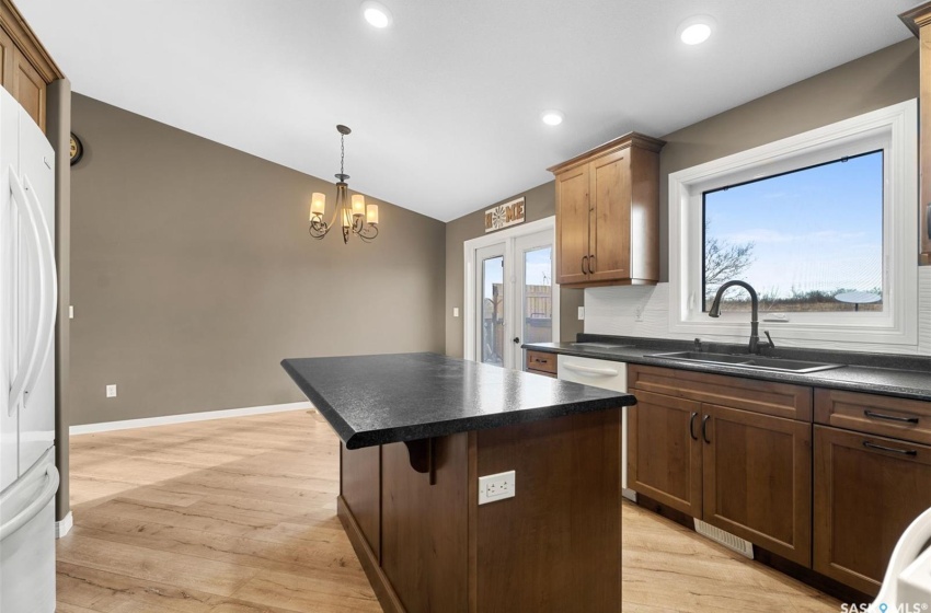 Kitchen with an inviting chandelier, sink, light hardwood / wood-style floors, pendant lighting, and a center island