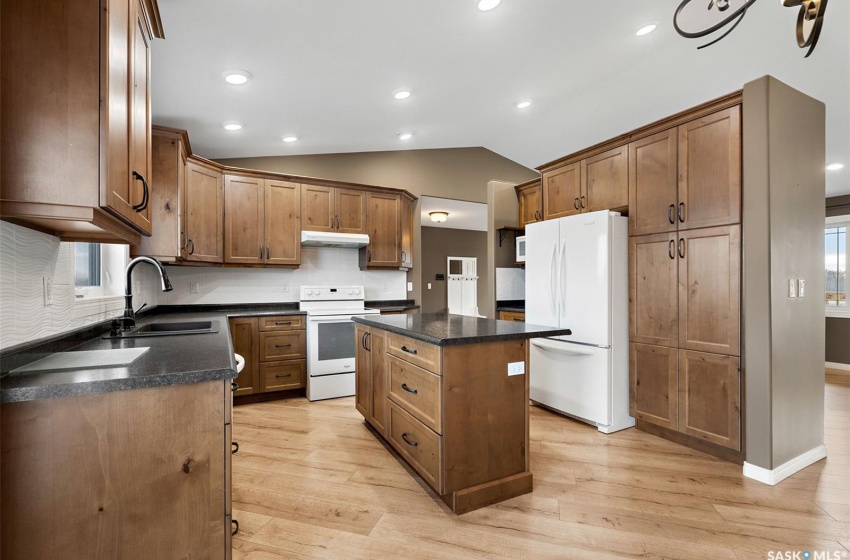 Kitchen with white appliances, sink, a kitchen island, and light hardwood / wood-style floors