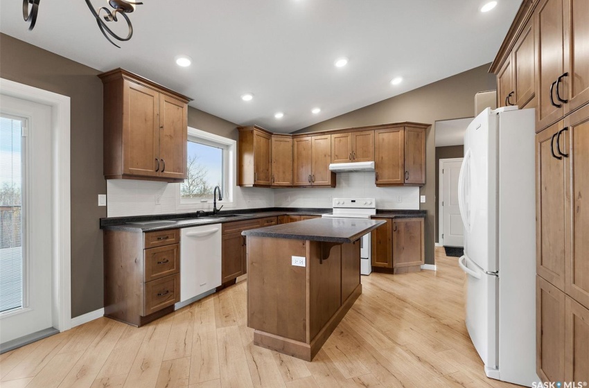 Kitchen with a center island, lofted ceiling, white appliances, and light hardwood / wood-style flooring