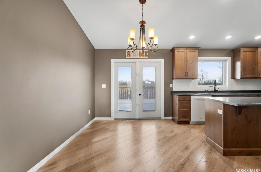 Kitchen with decorative light fixtures, an inviting chandelier, light hardwood / wood-style flooring, and backsplash