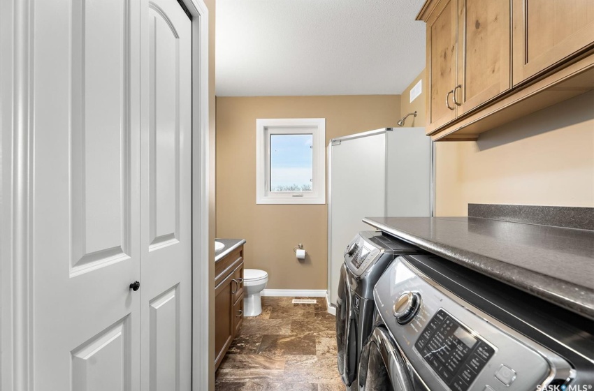 Washroom featuring dark tile floors, cabinets, and separate washer and dryer