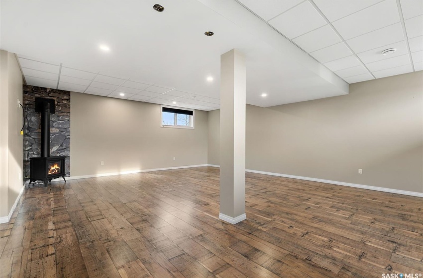 Basement featuring a wood stove, dark hardwood / wood-style flooring, and a drop ceiling