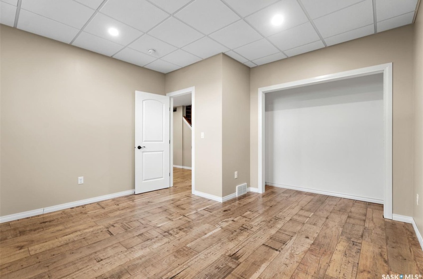 Unfurnished bedroom featuring light wood-type flooring and a drop ceiling