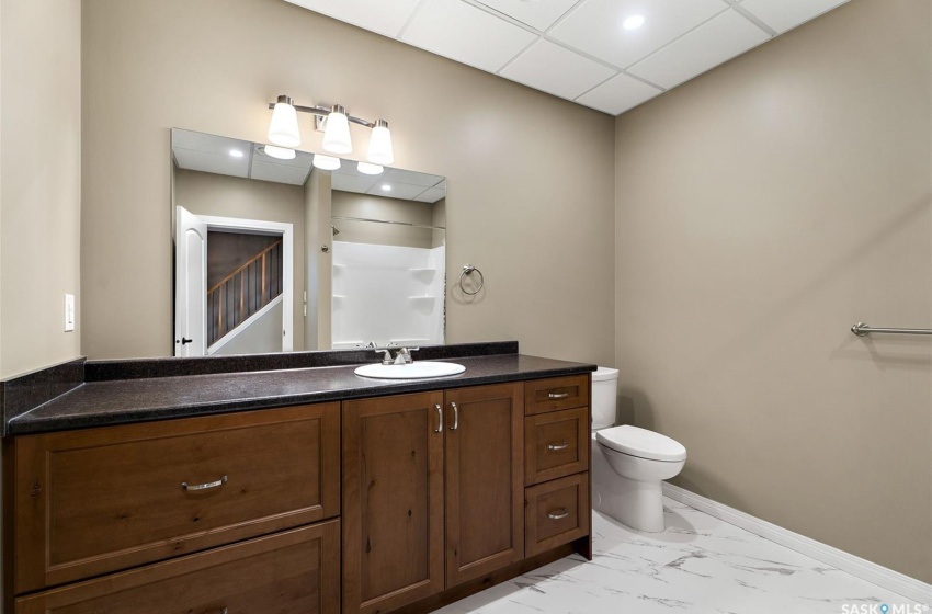 Bathroom featuring toilet, tile floors, a paneled ceiling, and vanity with extensive cabinet space