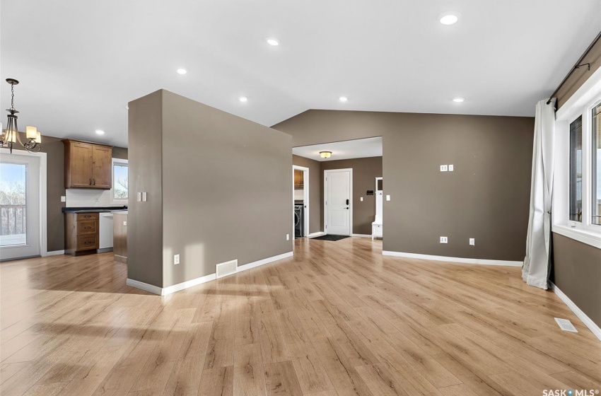 Kitchen featuring hanging light fixtures, an inviting chandelier, light wood-type flooring, white dishwasher, and lofted ceiling