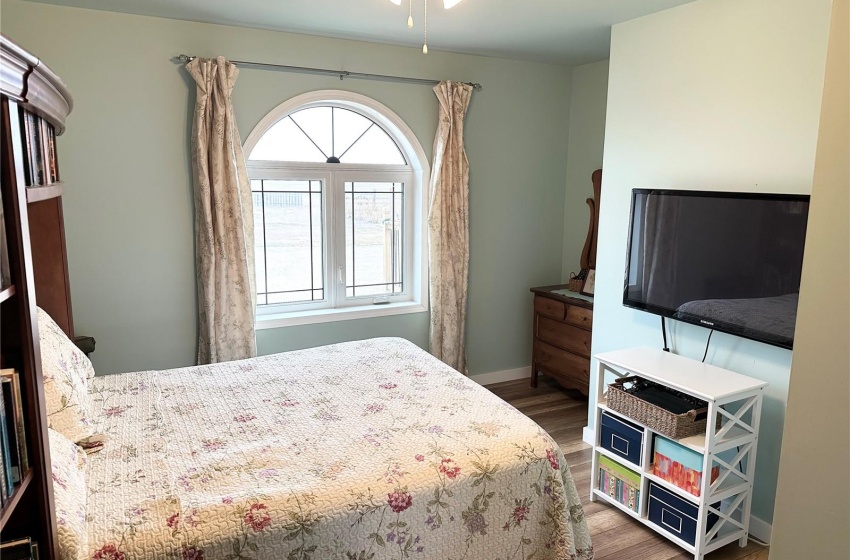 Bedroom with multiple windows, ceiling fan, and dark wood-type flooring