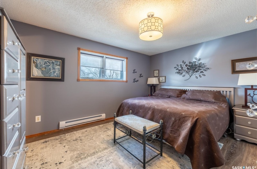 Bedroom featuring dark hardwood / wood-style floors, a textured ceiling, and a baseboard heating unit