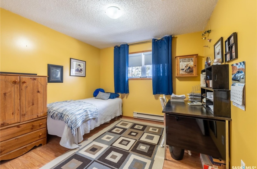 Bedroom featuring a baseboard radiator, light hardwood / wood-style flooring, and a textured ceiling