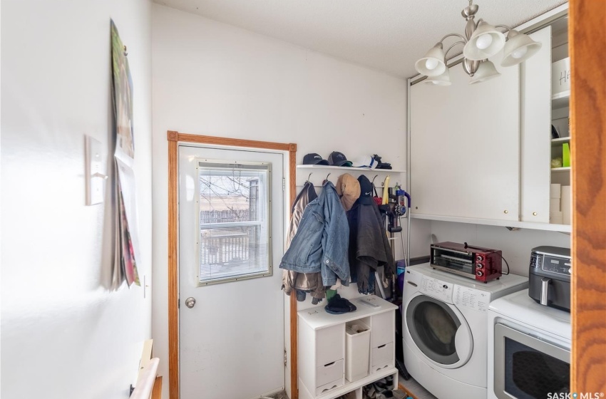 Clothes washing area with a notable chandelier, cabinets, and washing machine and clothes dryer