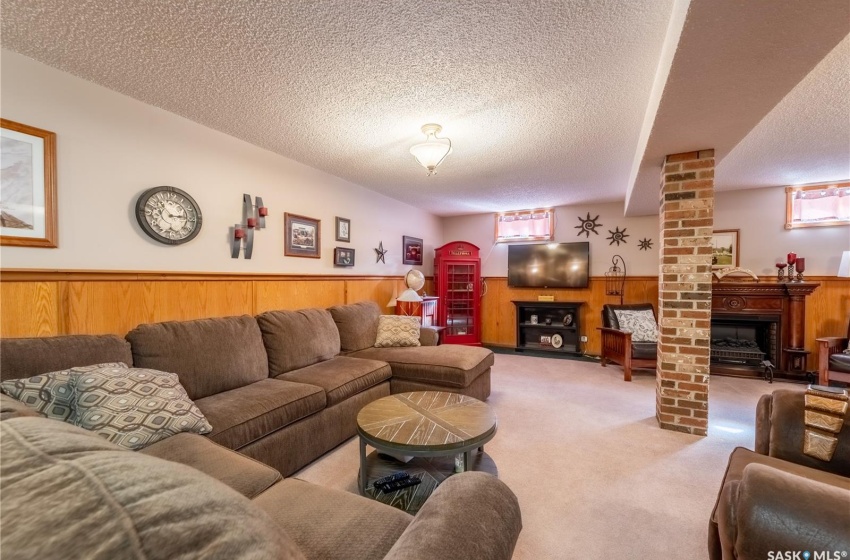 Carpeted living room with a textured ceiling and brick wall