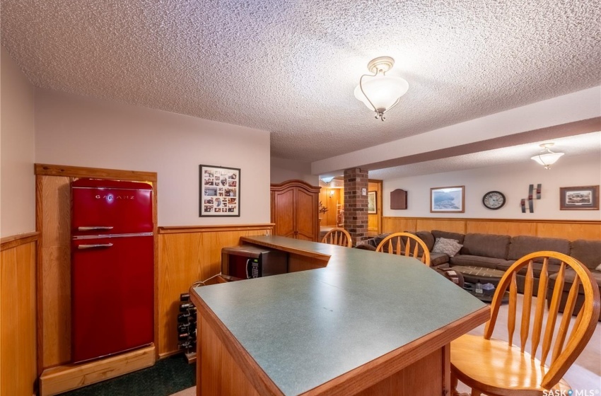 Kitchen featuring refrigerator, a textured ceiling, light colored carpet, and brick wall