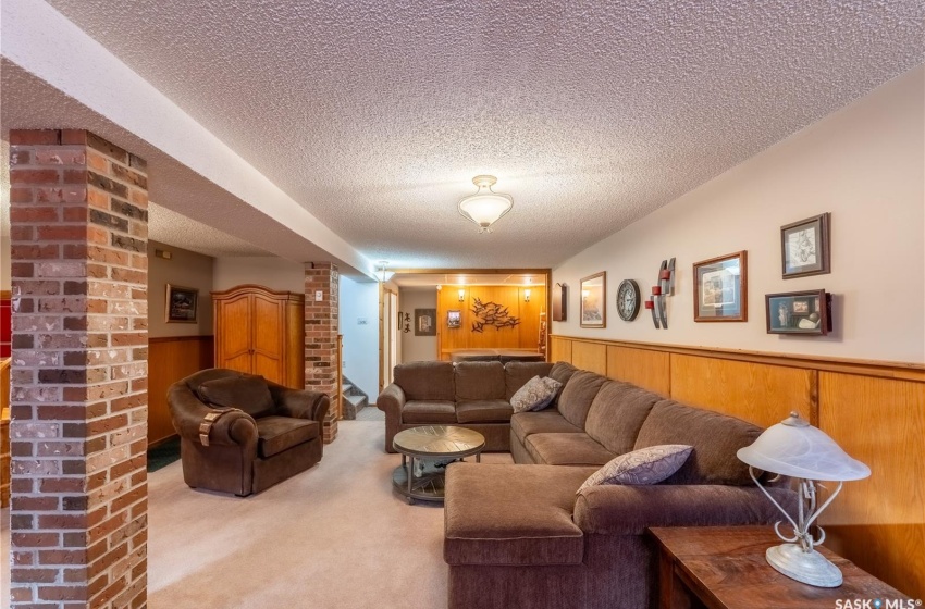 Carpeted living room featuring brick wall and a textured ceiling