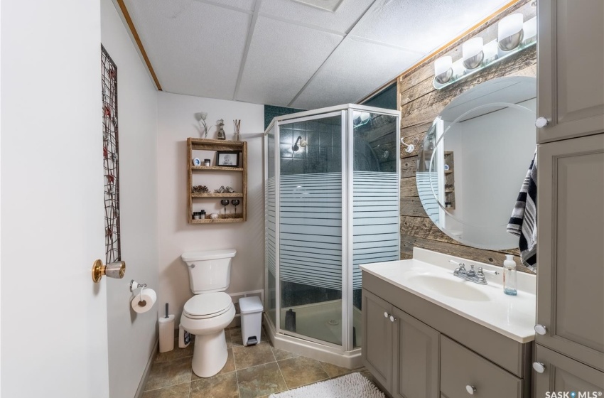 Bathroom featuring a shower with door, a drop ceiling, toilet, tile flooring, and vanity