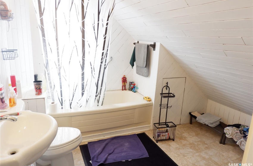 Full bathroom featuring tile flooring, vaulted ceiling, shower / tub combo with curtain, and sink