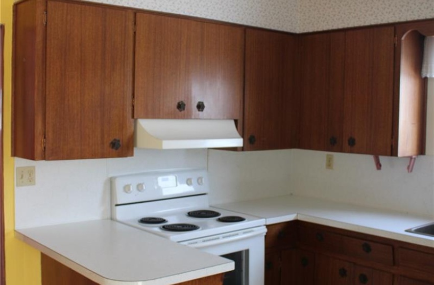 Kitchen featuring extractor fan, white electric range, and kitchen peninsula