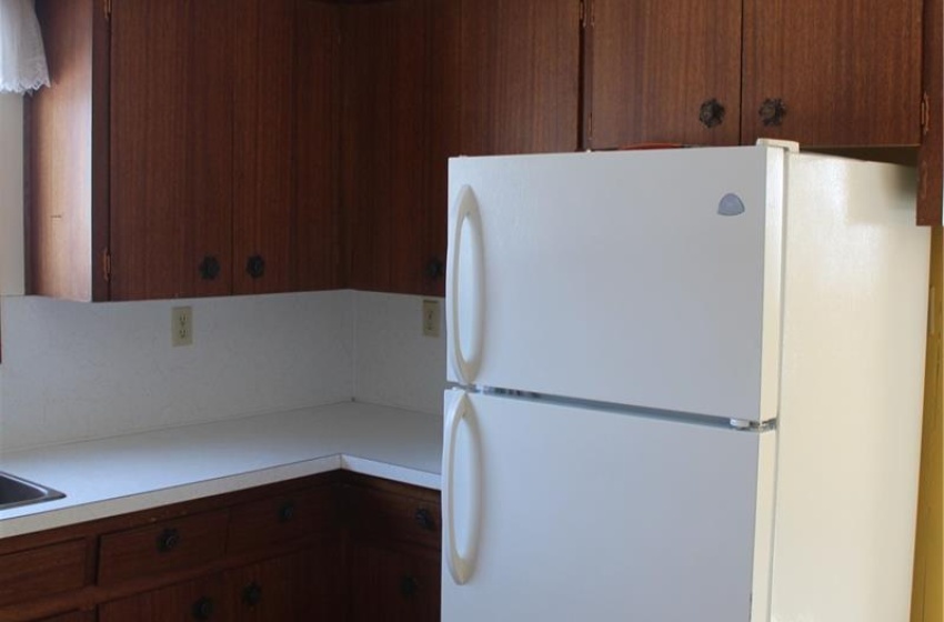 Kitchen with dark brown cabinets, white refrigerator, and sink