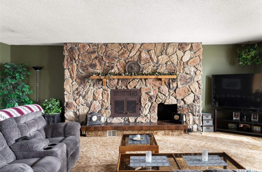 Carpeted living room with a stone fireplace and a textured ceiling