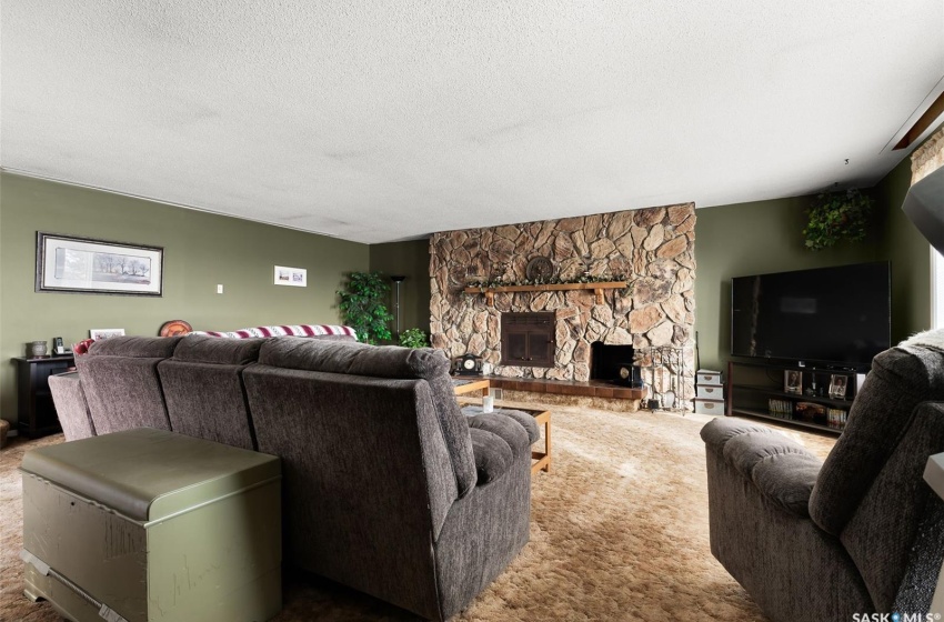 Living room featuring a stone fireplace, dark colored carpet, and a textured ceiling