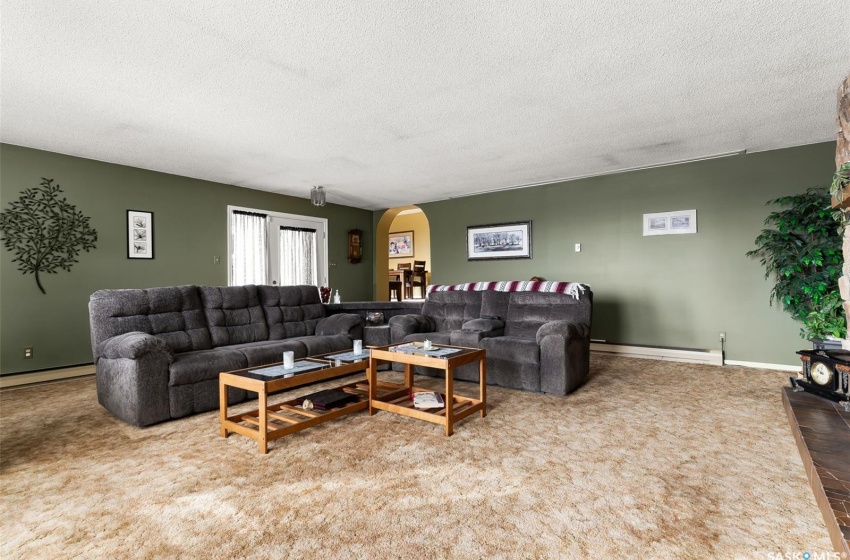 Living room with carpet flooring, a baseboard heating unit, and a textured ceiling