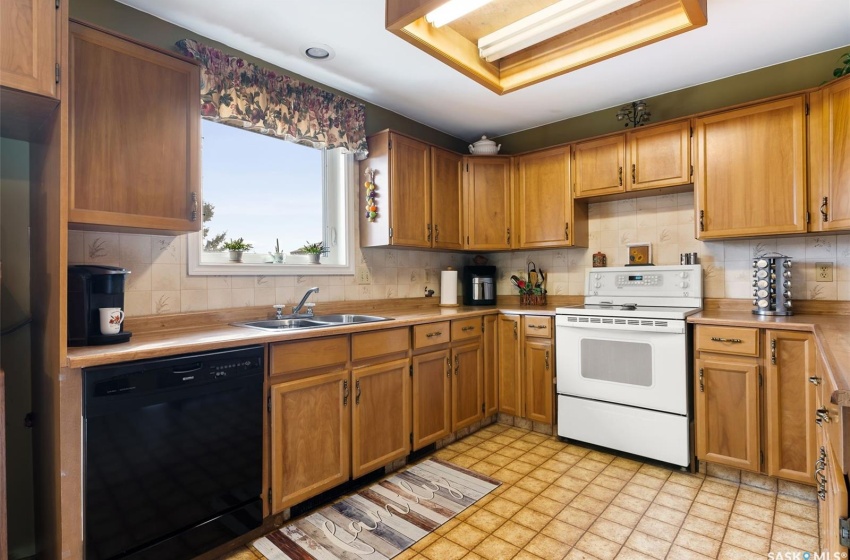 Kitchen with sink, black dishwasher, backsplash, and white electric range