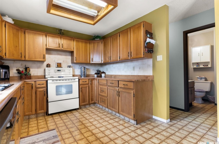 Kitchen with white electric stove, dishwasher, light tile floors, and backsplash