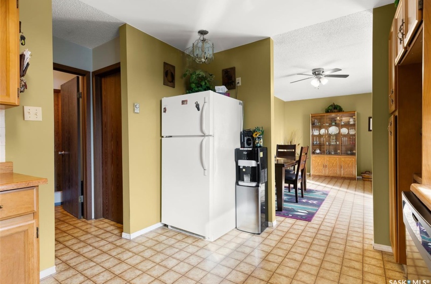 Kitchen featuring light tile floors, white appliances, ceiling fan with notable chandelier, and a textured ceiling