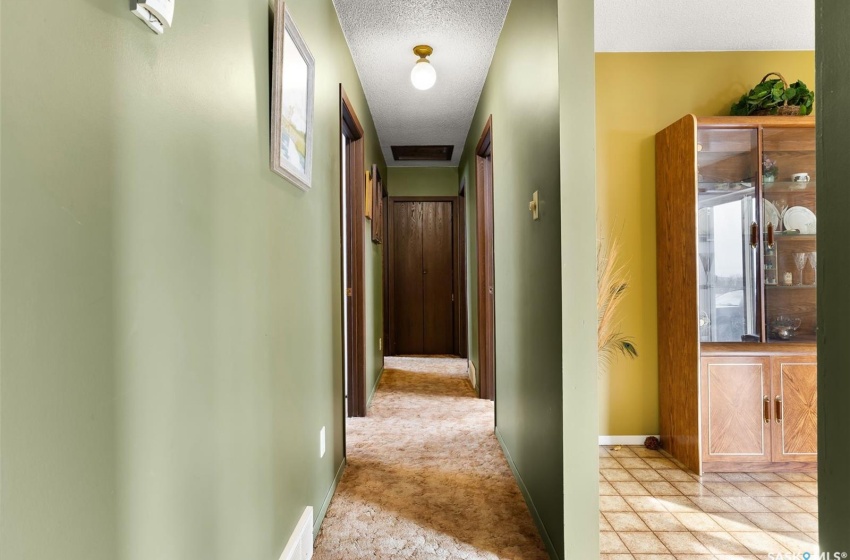 Hallway with light carpet and a textured ceiling