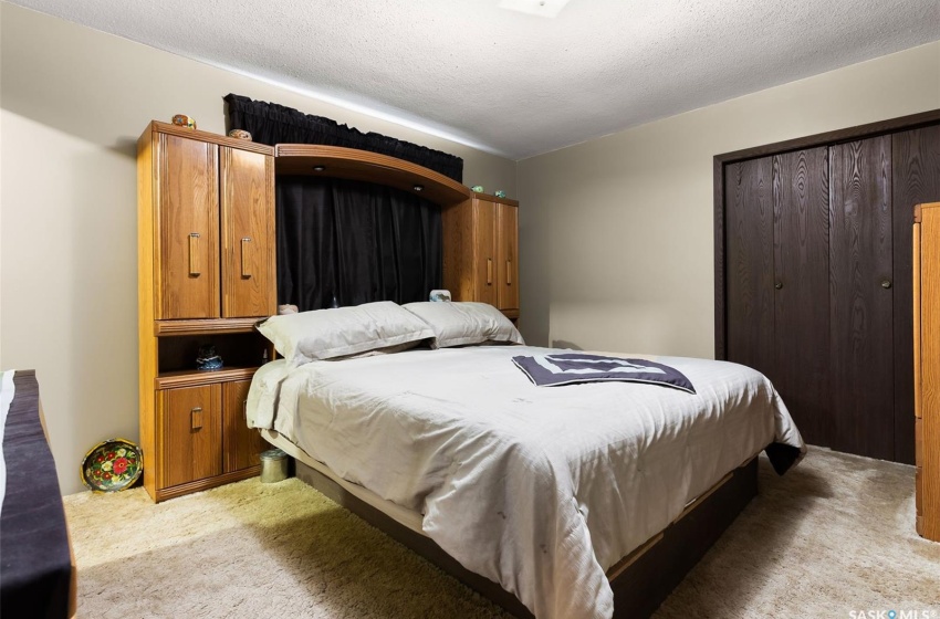 Bedroom with a textured ceiling, light colored carpet, and a closet