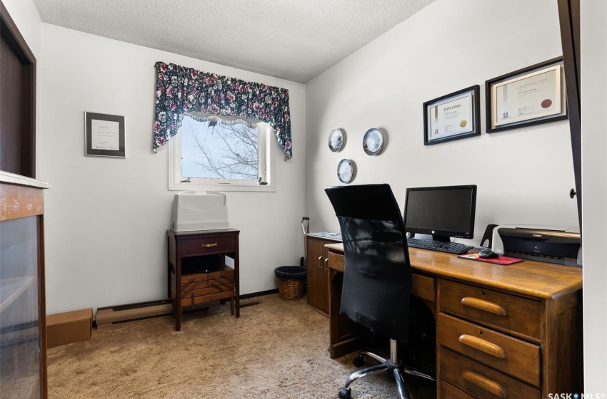 Carpeted home office featuring a textured ceiling