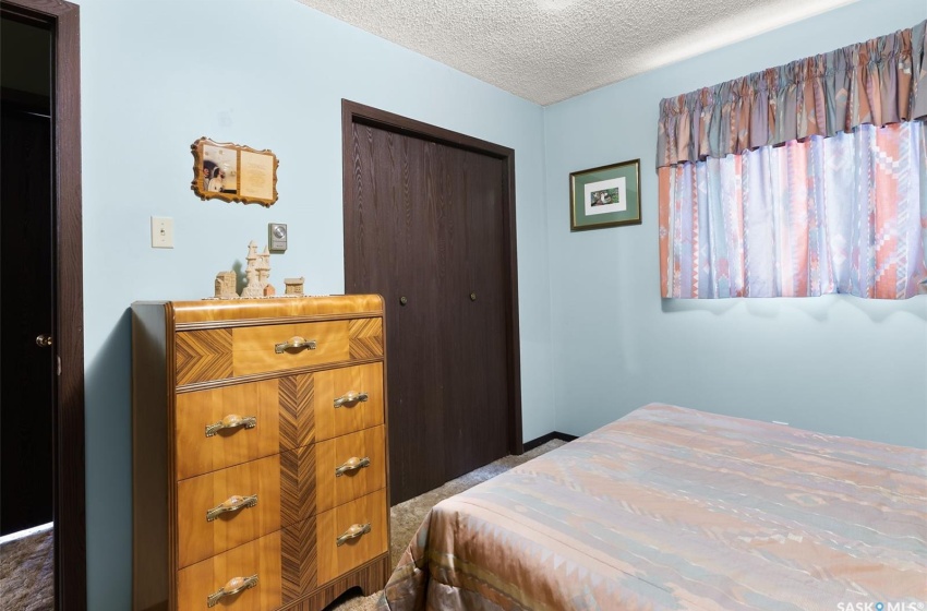 Carpeted bedroom with a closet and a textured ceiling