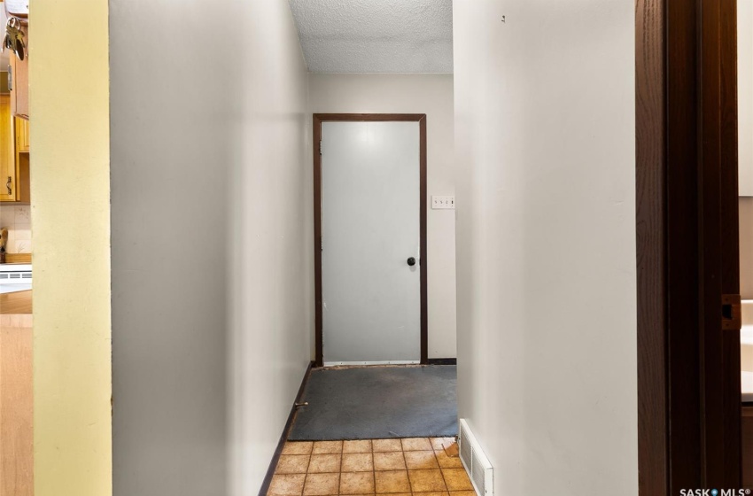 Corridor with a textured ceiling and light tile floors