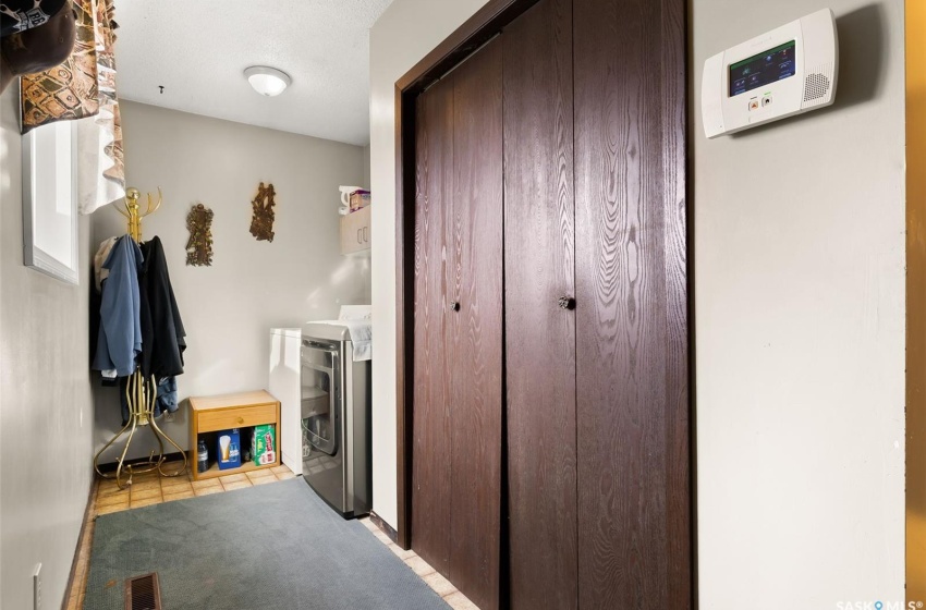 Corridor featuring washer and dryer and light tile floors