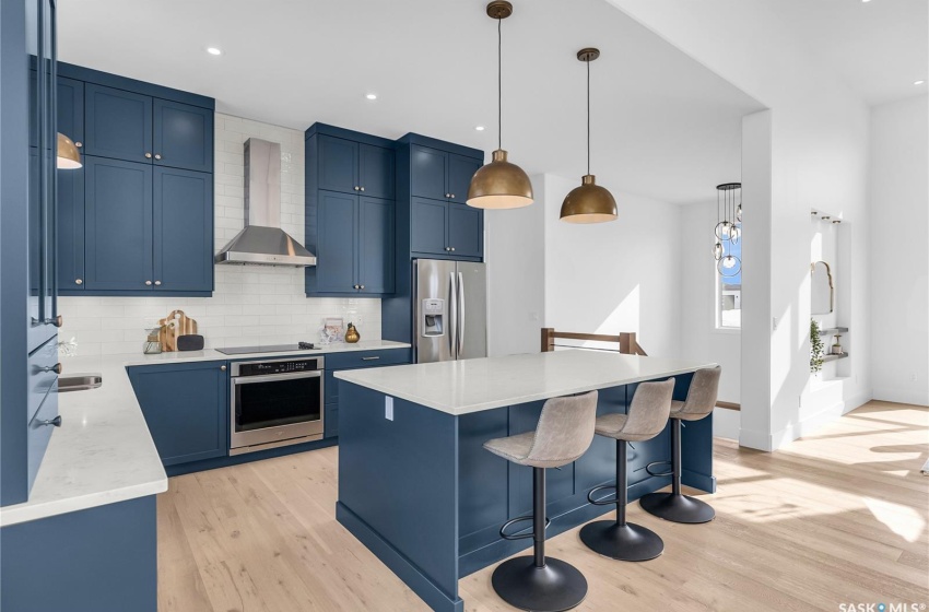 Kitchen featuring a center island, tasteful backsplash, exhaust hood and appliances with stainless steel finishes.