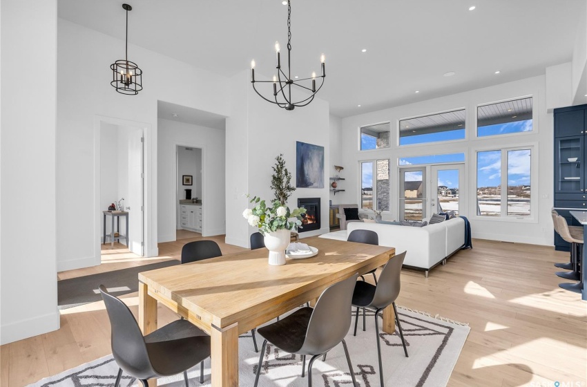 Dining space with a notable chandelier, light flooring and high ceiling.