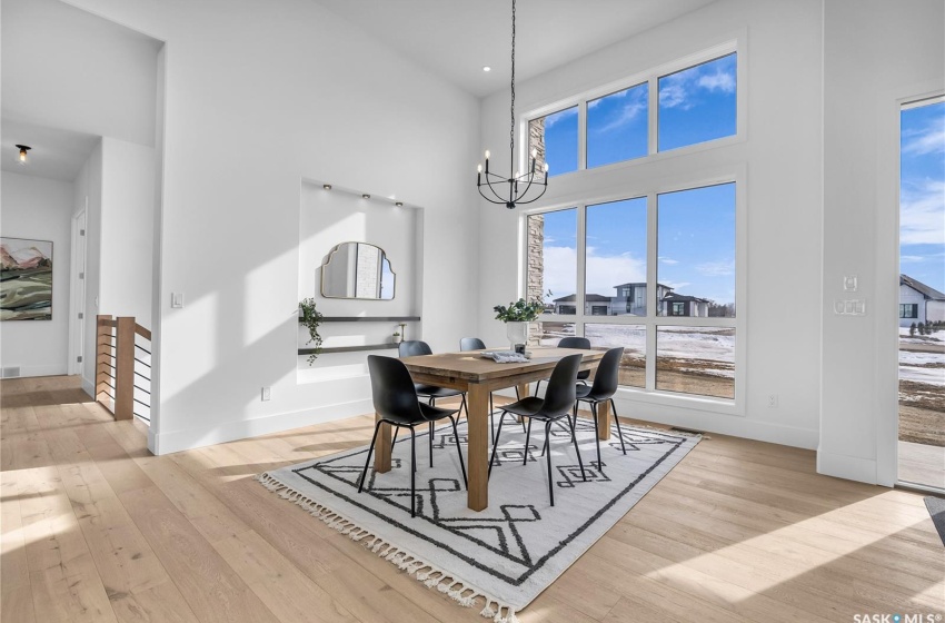 Dining space with a notable chandelier, light flooring and high ceiling.