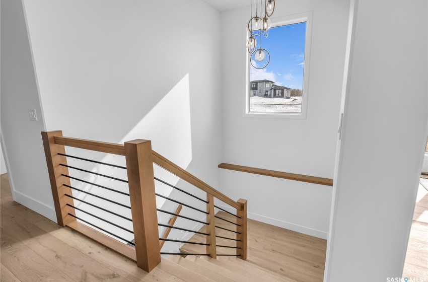 Stairway with an inviting chandelier and light flooring