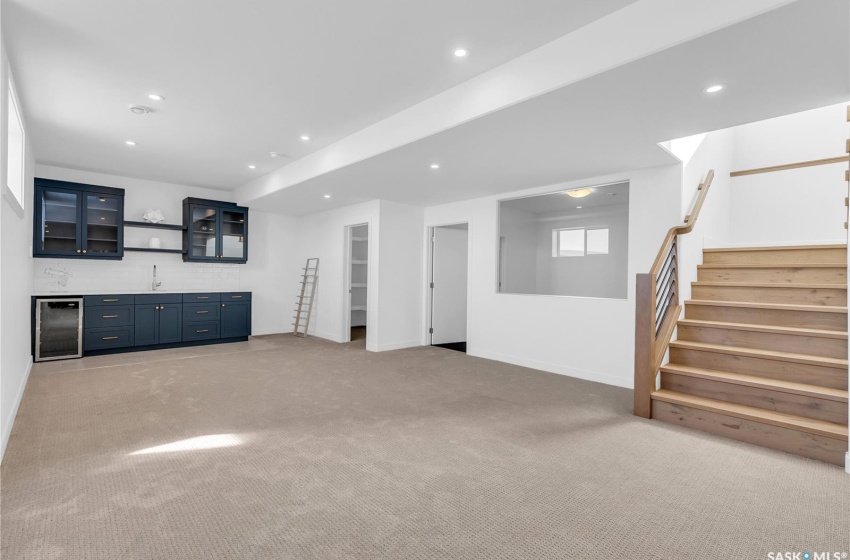 Basement with light colored carpet, bar and beverage cooler