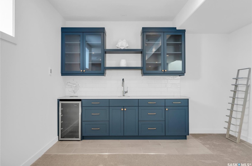 Basement with light colored carpet, bar and beverage cooler