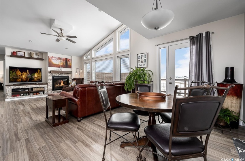 Dining space featuring a stone fireplace, light hardwood / wood-style floors, vaulted ceiling, and ceiling fan