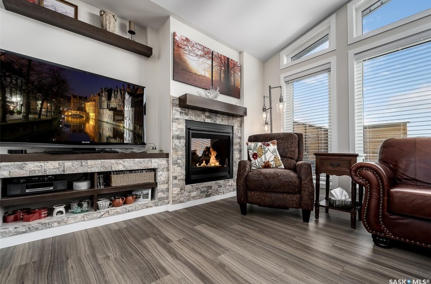 Sitting room featuring plenty of natural light, lofted ceiling, a stone fireplace, and dark hardwood / wood-style flooring