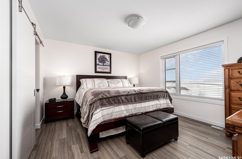 Bedroom with a barn door and hardwood / wood-style floors