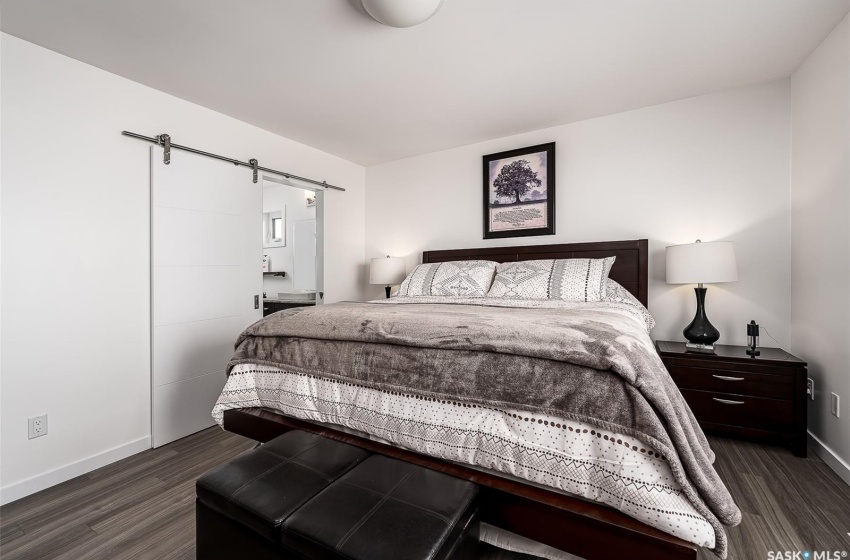 Bedroom featuring a barn door and dark hardwood / wood-style floors