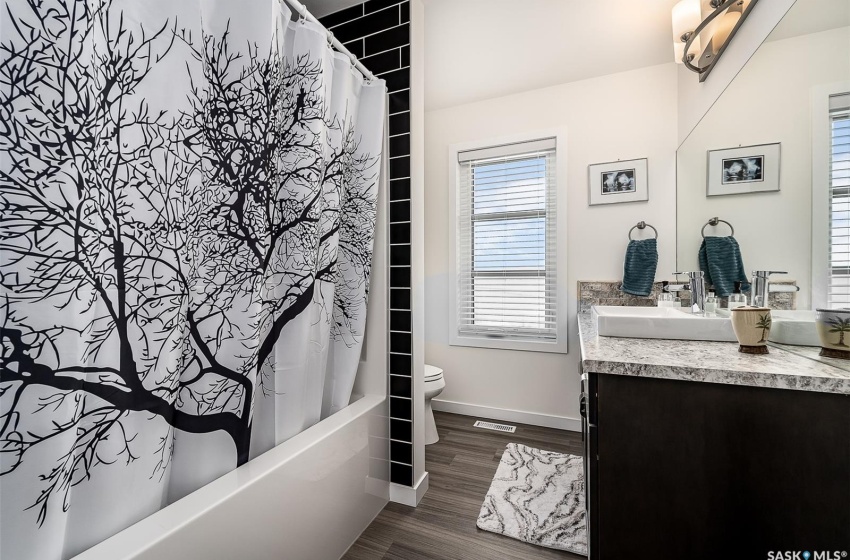 Full bathroom featuring hardwood / wood-style floors, toilet, shower / bath combo with shower curtain, and oversized vanity